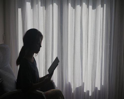 A well-lit cozy reading corner beside a large window with natural daylight