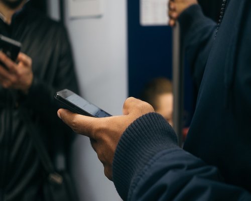Close up of hands holding a smartphone while commuting